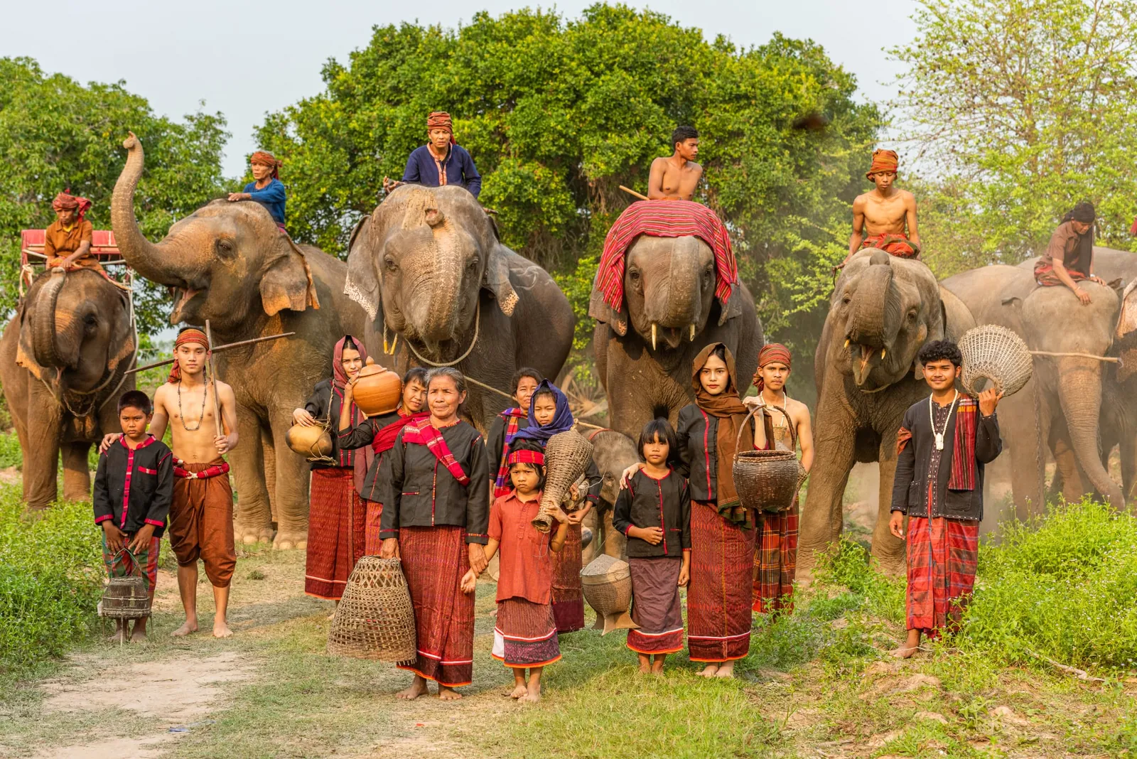 Generations of Kuy villagers in traditional dress standing with their elephants